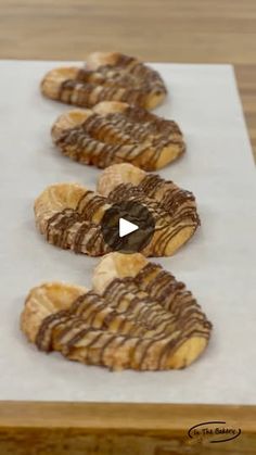 the cookies are lined up and ready to be baked in the oven on paper with chocolate drizzled over them