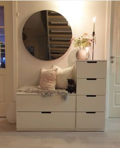 a white dresser with drawers and a mirror above it