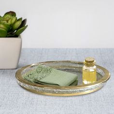 a bottle of olive oil on a tray next to a potted plant