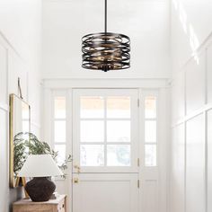 a hallway with white walls and wooden flooring has a light fixture hanging from the ceiling