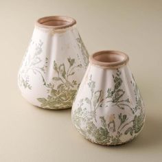 two white vases with green designs on them