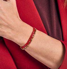 a woman wearing a red and gold beaded bracelet on her wrist, with the clasp undone