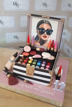 a birthday cake with makeup and lipstick on it's display stand in front of a wall