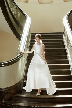 a woman in a white dress is walking down the stairs