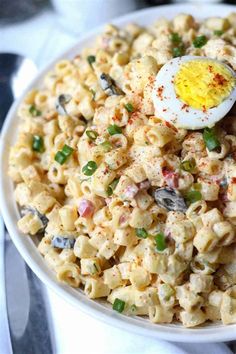 a white bowl filled with macaroni salad and an egg