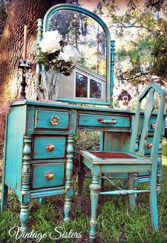 an old dresser and chair are painted turquoise with flowers on the mirror's edge