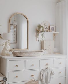 a baby's room with white dresser and mirror