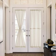 a white door with curtains hanging from it's sides and a table on the other side