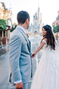 a bride and groom holding hands in front of the castle at disney's magic kingdom