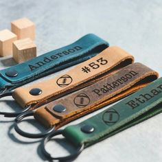 three personalized leather keychains with name tags attached to them, sitting on a table