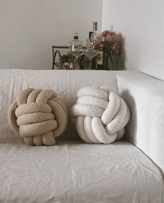 two pillows sitting on top of a white couch