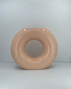 a beige vase sitting on top of a white table