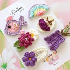 several crocheted items are displayed on a white card with pink, purple, and green flowers