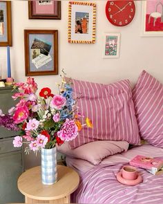 a bed with pink and white striped sheets, flowers in a vase on the end table