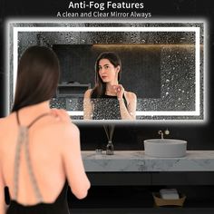 a woman standing in front of a bathroom mirror looking at her reflection on the wall