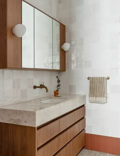 a bathroom with wooden cabinets and marble counter tops, along with a white tiled wall