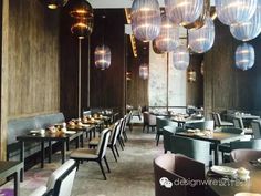 an empty restaurant with many tables and chairs in front of the wall, along with hanging lights