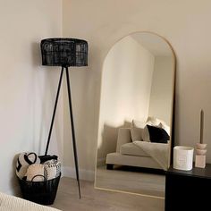 a large mirror sitting next to a black basket on top of a wooden floor in a room