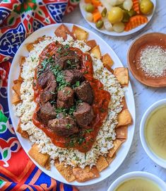 a plate with meatballs, rice and sauces on it next to bowls of dipping sauce