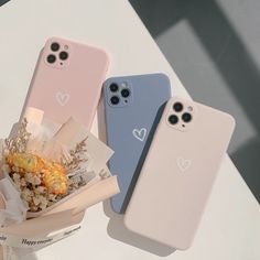 two cell phones sitting next to each other on top of a white table with flowers