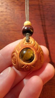 a hand holding a small bead with a yellow stone in it's center