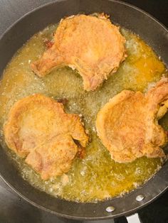 three pieces of meat cooking in a frying pan