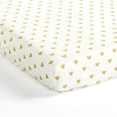 a white and gold bed sheet with hearts printed on the top, in front of a white background