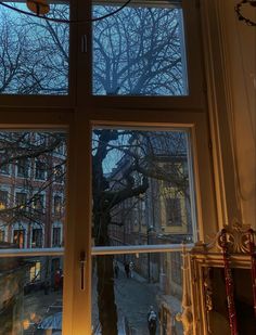 an open window with the view of buildings and trees outside at night, in front of it