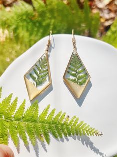 Elevate your style with the natural charm of Resin Pressed Green Fern Leaves Dangled Drop Earrings, a handmade masterpiece that captures the timeless beauty of botanical wonders. These earrings are a testament to creativity and craftsmanship, blending the lush greenery of real fern leaves with an elegant and contemporary design. Each earring showcases meticulously pressed green fern leaves, preserved in resin to maintain their intricate details and vibrant shades of green. The result is a captivating display of nature's grace, transformed into wearable art that brings a touch of the garden's beauty to your ensemble. The dangled drop design adds a contemporary twist, offering an elegant and versatile option that effortlessly complements various styles and occasions. Whether you're seeking t Fern Earrings, Grace Symbol, Plant Earrings, Botanical Earrings, Fern Leaves, Drop Design, Botanical Beauty, Drops Design, Meaningful Gifts