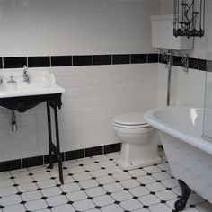 a white toilet sitting next to a bath tub in a bathroom with black and white tiles