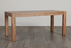 a wooden table sitting on top of a hard wood floor next to a white wall