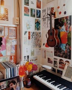 a room with a piano, musical instruments and pictures on the wall above it is a vase filled with flowers