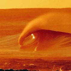 the sun is setting over an ocean with a large wave in the foreground and orange sky above it