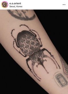 a tattoo on the arm of a person with a bug in it's center