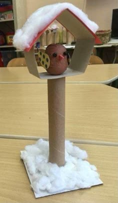 a birdhouse made out of toilet paper on top of a wooden table with clouds