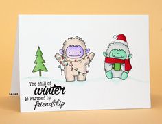 a card with two cartoon animals wearing christmas hats and scarfs, one is holding a snowman