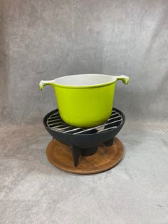 a green and white bowl sitting on top of a black grill with a spatula