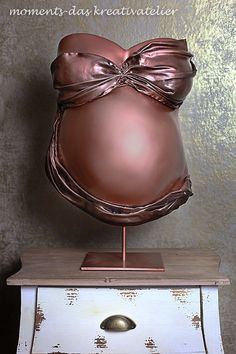 an old dresser with a large brown vase on top of it's base and a gold bow tie around its neck