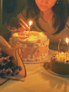 a woman sitting in front of a cake with lit candles