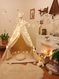 a white teepee with lights on it in a living room next to a fireplace