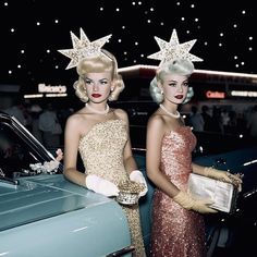 two women standing next to each other in front of a blue car with stars on it