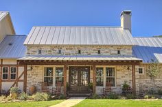 a house with a metal roof and wooden front door is featured in this photo from the outside