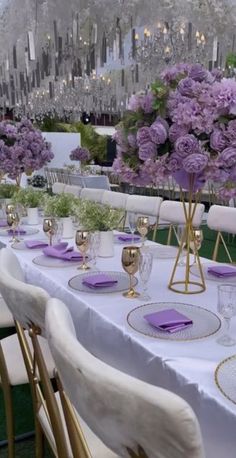 the tables are set with purple flowers and place settings for guests to sit down at