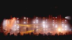 a group of people standing on top of a stage with lights in the dark behind them