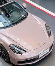 a pink sports car is on display in a showroom with its hood up and the top down