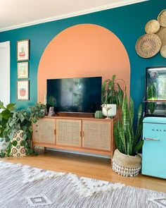 a living room filled with lots of plants next to a flat screen tv on top of a wooden cabinet