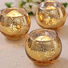 three gold colored candles sitting on top of a table