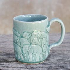 a green ceramic mug with elephants on it