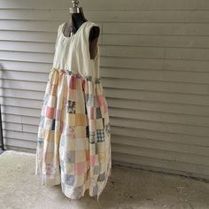 a dress made out of old clothing hanging on a hanger in front of a house