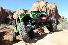 a green four - wheeler is going up a hill in the desert